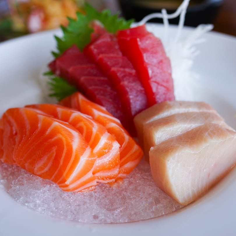 Sashimi platter with tuna, salmon, and white fish slices on a bed of ice.